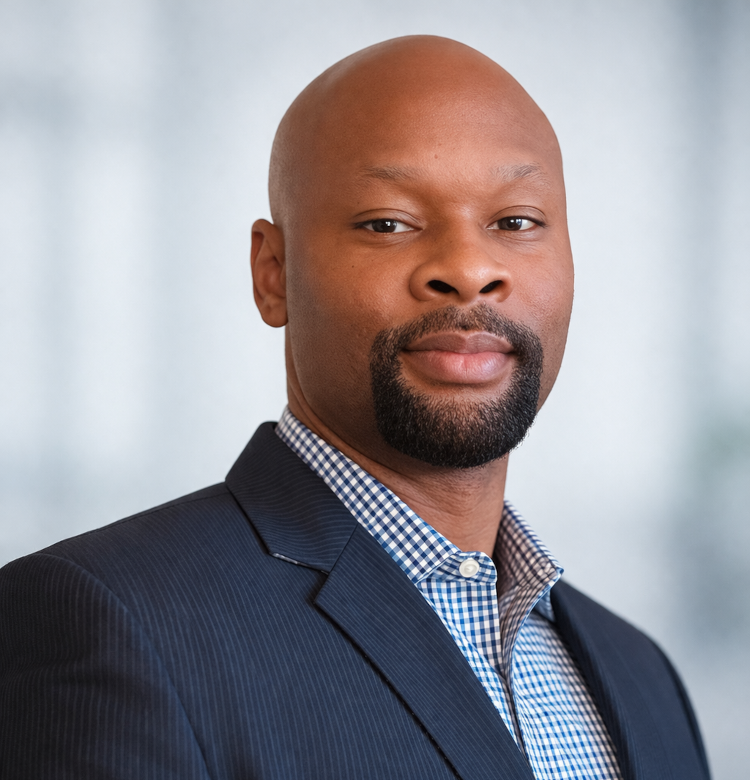 Professional headshot of a bald Black man in a navy pinstripe suit and blue checkered shirt, facing the camera.